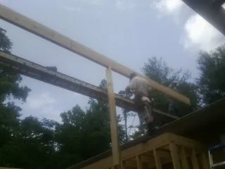 Carpenter setting a ridge beam over a new addition frame — Ice Dam Removal by Roofing Brothers in Jamaica Plain