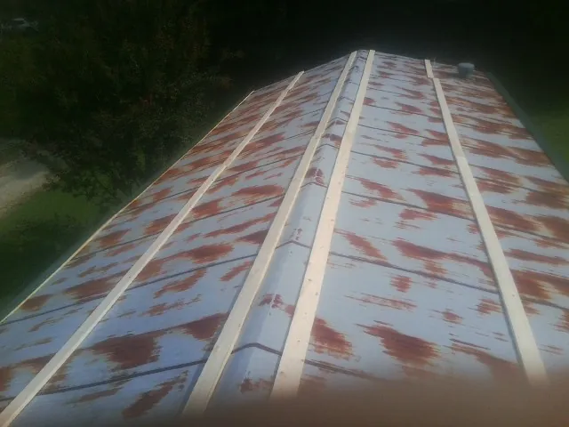 Rusted metal roof panels with new wood purlins before replacement — Storm Damage Roof Repair in Jamaica Plain by Roofing Brothers