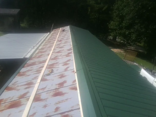 Old rusted panels beside newly installed green metal roofing — Wind Damage Roof Repair by Roofing Brothers in Jamaica Plain