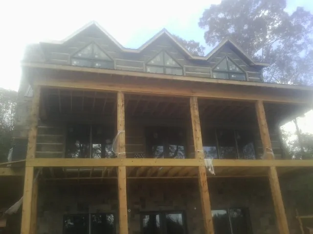 Dormers and porch framing on a large log home under construction — Roof Coating work by our crew in Jamaica Plain
