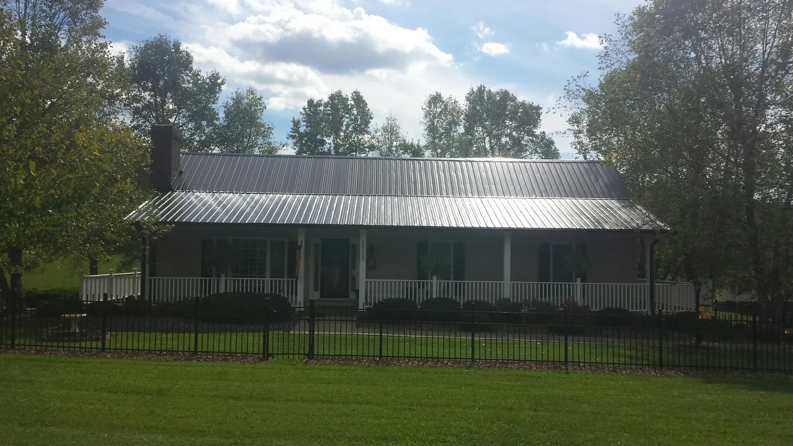 Gray metal roof on a brick ranch with a full width front porch — Gutter Guard Installation work by our crew in Jamaica Plain