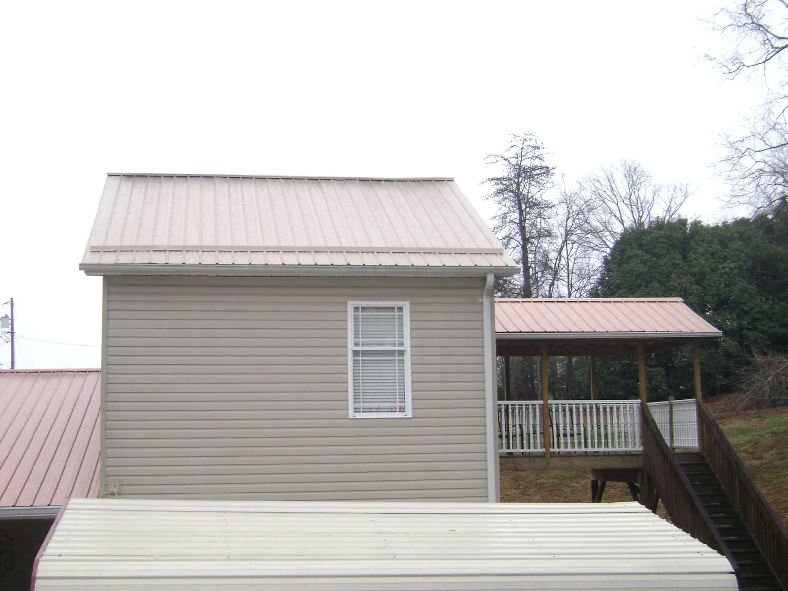 Tan metal roofs on a two story addition and attached porch, from a Roof Replacement job in Jamaica Plain