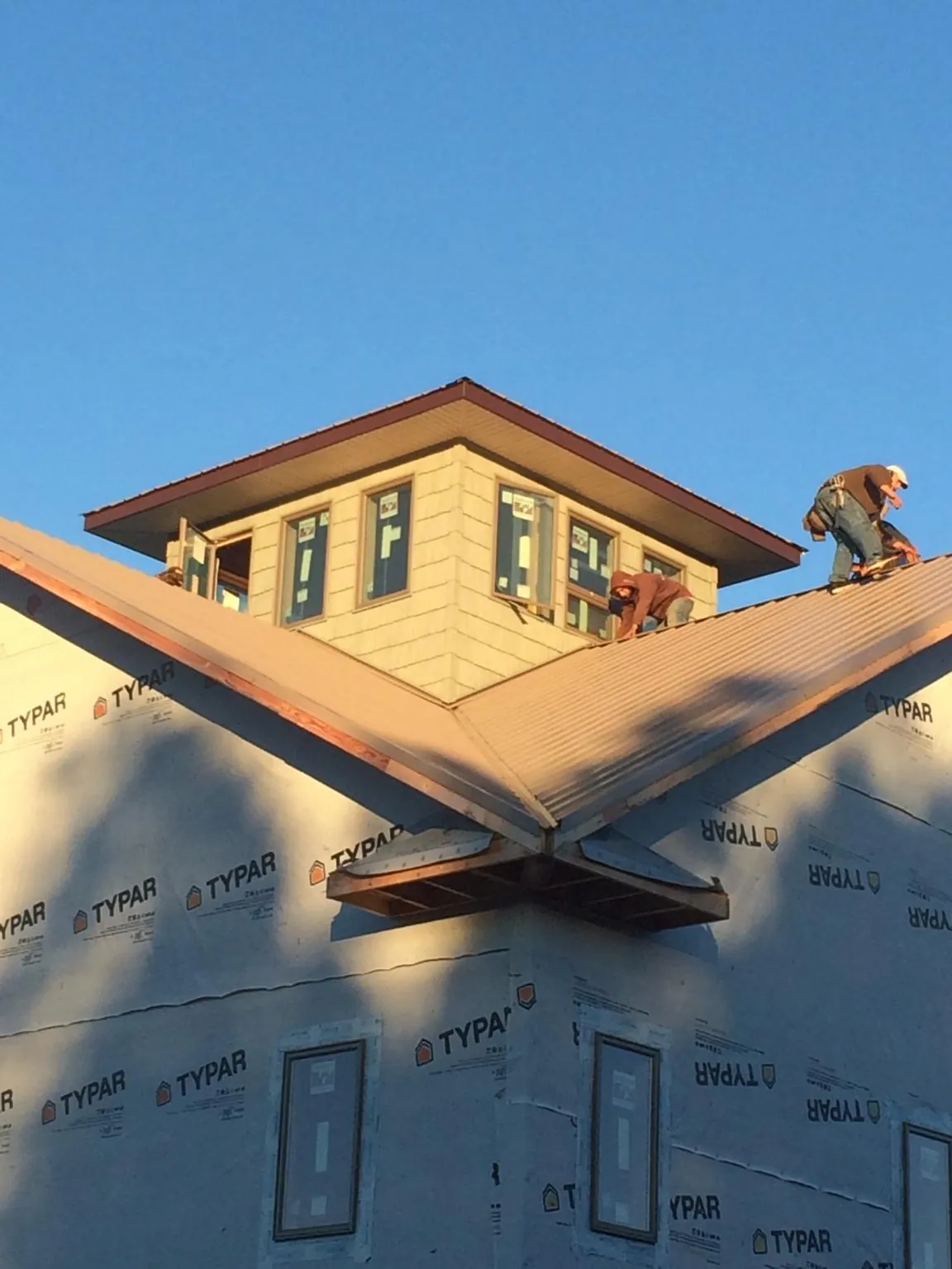 Roofers working around a rooftop cupola on a new metal roof at sunset — Roof Waterproofing in Jamaica Plain by Roofing Brothers